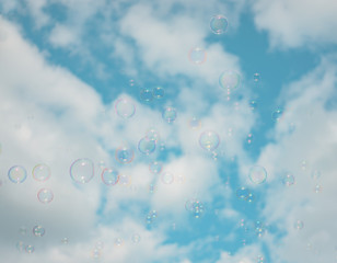 Abstract background : Beautiful soap bubbles reflecting various color floating on sky and white cloud background. Filter color : Aqua.