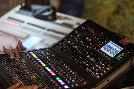 An expert adjusting audio mixing console on control desk.