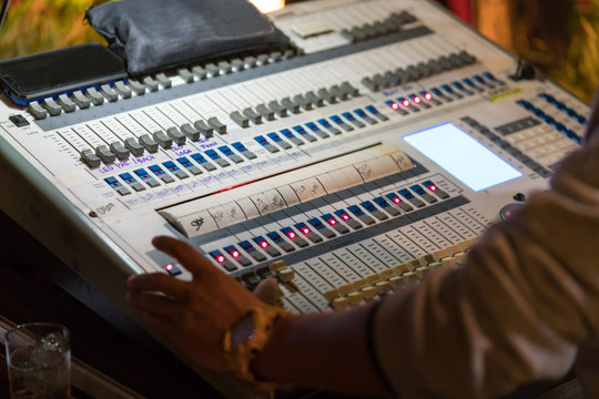 An expert adjusting audio mixing console on control desk.