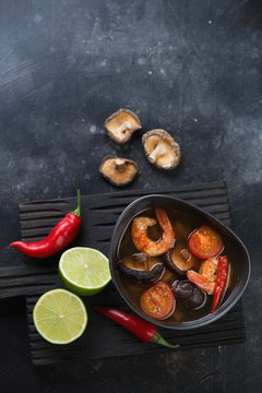 Thai traditional Tom Yum soup on a dark metal background, view from above with space, vertical shot