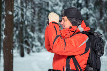 Fototapeta na wymiar lonely lost tourist man in winter forest with binoculars