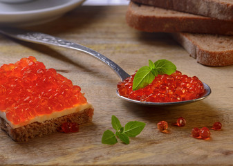 Sandwich with red caviar and on a metal spoon