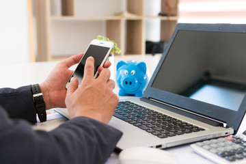 Hand using smart phone,mobile payments online shopping, Business man working in wooden desk with laptop and telephone at work space.