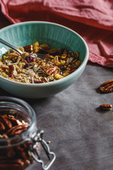 Muesli with dried berries and pecan nuts in ceramic bowl. Close-up of breakfast table.
