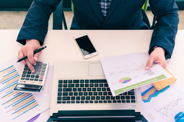 Top view of business man working on a desk at work office. Business people are analyzing plans and using calculators.Business people are reading a business transaction. Vintage tone
