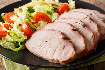 Baked pork tenderloin with vegetable salad close-up on a plate. horizontal