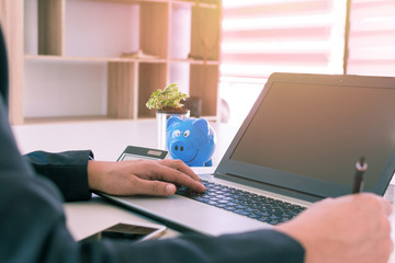 Close up shot businessman writing notes on notebook at office. Businessmen are using a laptop computer on a desk. Close up of hand of businessman typing on keyboard. Vintage tone