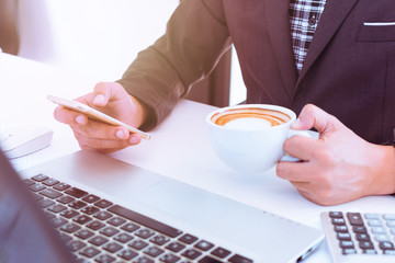 Top view of Businessmen are relaxing with coffee while using smart phone in the workplace. Business people are relaxing at the desk with a cup of coffee. Vintage tone