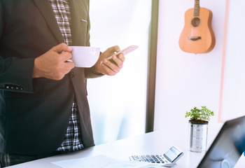 Businessmen are standing relaxed, holding a cup of coffee while they are using the smart phone.Business people are using the phone to contact a partner.Online shopping concept. mobile banking concept.