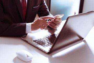 Business man, technology and internet concept, Close up of male hands with smartphone. Online shopping or banking concept, credit ,debit. Businessman using smart phone with conputer laptop on desk.