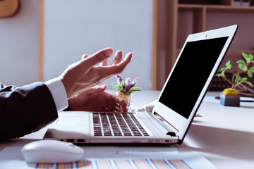 Business are using laptop on desk indoors with afternoon hard light.The boss is making a problem gesture with work or business.