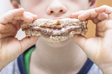 Closeup of boy eating sweet sandwich with chocolate