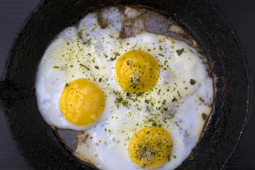 appetizing fried eggs in an old frying pan