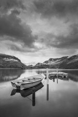 Beautiful  black and white Winter landscape image of Llyn Nantlle in Snowdonia National Park with snow capped mountains in background