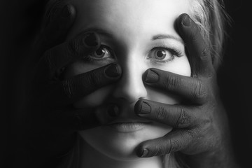 Frightened blonde woman grabbed by black hands on her face artistic conversion