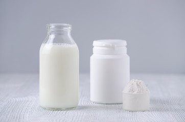 glass bottle of milk and powder on gray background