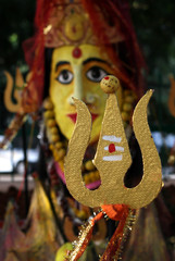 Closeup of Trishul or trident and Indian Hindu Goddess in the background