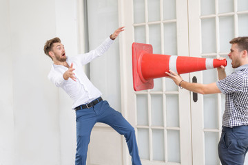 Handsome young guy holding traffic cone and making shout to his boyfriend
