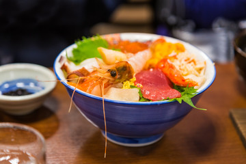Bowl of sashimi, Japanese raw seafood, including shrimp, tuna, crab meet, squid, and fish egg