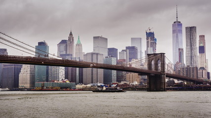 Fototapeta premium Manhattan and Brooklyn Bridge, New York City. Fast clouds float over the skyscrapers, cloudy weather, heavy traffic on the river