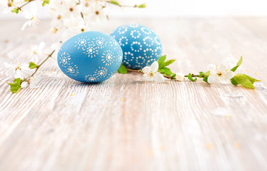 Closeup on blue Easter eggs with flowers on wooden table, space