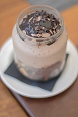In a glass jar a dessert with different textures of chocolate. From above.