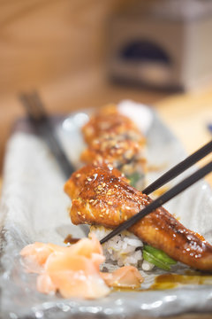Chopsticks hold on sushi freshwater eel grilled.