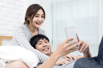 Asian Couple or lover in love using phone on the bed.