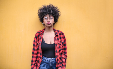 Street fashion girl posing in front of a yellow wall