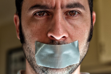 Close up portrait of a man with duct tape over his mouth