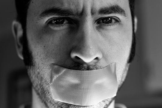 Close Up Portrait Of A Man With Duct Tape Over His Mouth