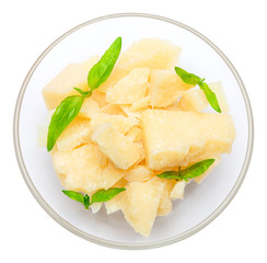 Parmesan cheese pieces in glass bowl on white background