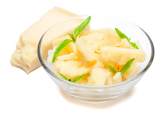 Parmesan cheese pieces in glass bowl on white background
