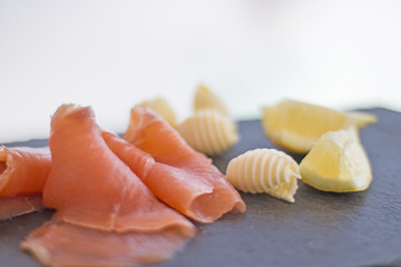 Small slices of smoked salmon with some curls of butter and lemon wedges.