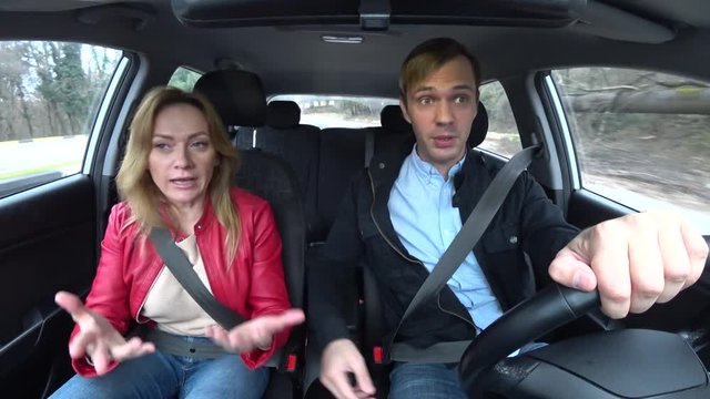 a couple of men and women ride in a car, they quarrel, and scream at each other. 4k