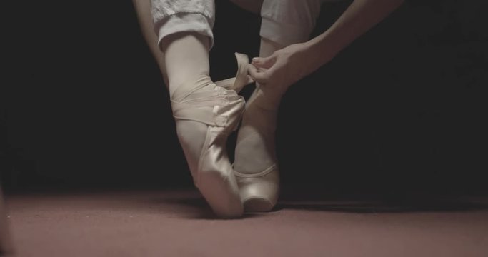 Ballet dancer putting on her ballet shoes