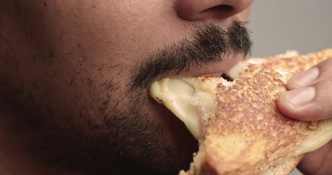 Black man eats a sandwich closeup with a streaching cheese