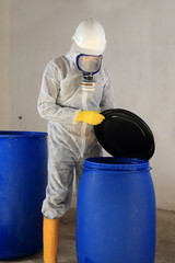 Arbeiter mit Atemschutz öffnet Tonne mit Chemikalien