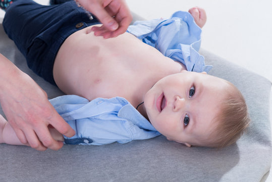 Cute little baby boy in blue shirt and jeans lying on the blanked and posing in the photo studio on white background