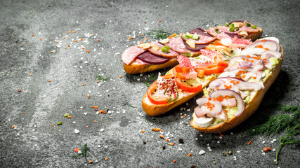 Sandwiches with meat, salami, seafood and fresh vegetables.