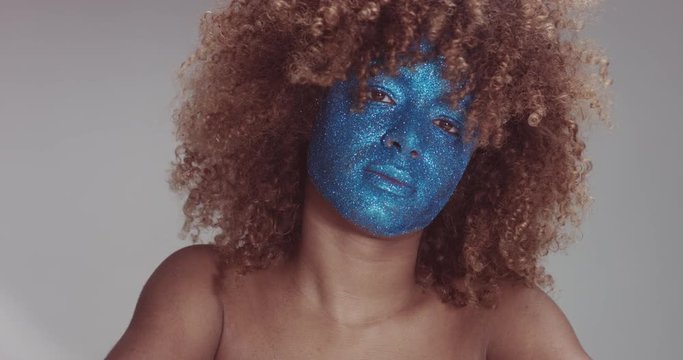 black woman with blond hair and blue glitter face makeup portrait