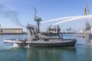 Navy firefighting ship in action. fire fighting a vessel in water from a ship.