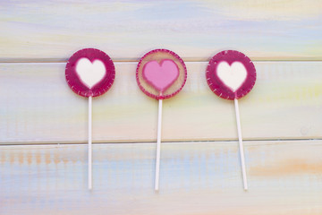 Lolipops with hearts on wooden background