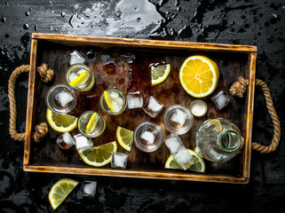 Vodka with lemon and ice on a wooden tray.