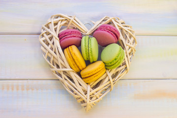 Woven heart with macaroons on wooden background