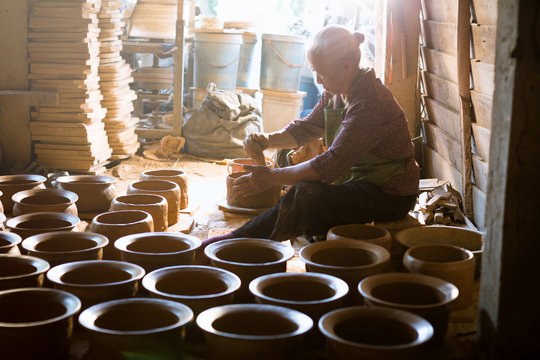 Potter at work. Close-up of woman making ceramic pot on the pottery wheel