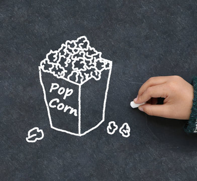 Little boy drawing popcorn on a blackboard