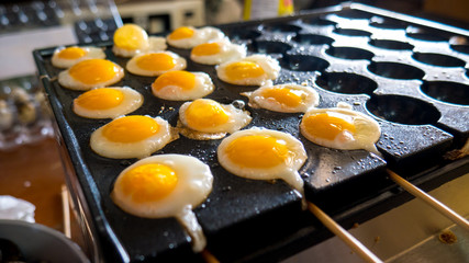 Fried quail eggs cooking on stove.