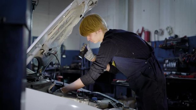 auto mechanic is checking internal faults in important car systems and robustness of connections, in automobile repair workshop