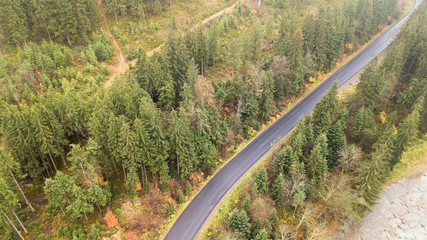 Aerial view of road in the middle of the mountains, on which pine trees grow